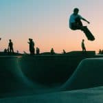 man doing trick at skateboard park during sunset