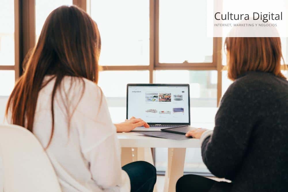 two women talking while looking at laptop computer