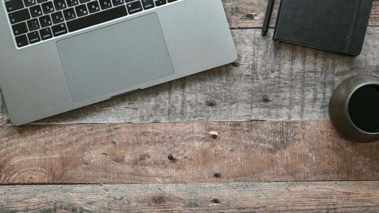 Competencias digitales en el trabajo: portátil y libreta en un escritorio de madera
