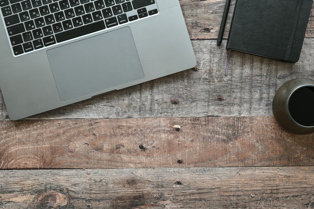 Competencias digitales en el trabajo: portátil y libreta en un escritorio de madera